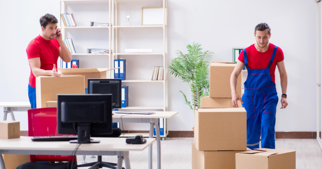 Office relocation team packing boxes and preparing equipment for moving in a modern office setting.