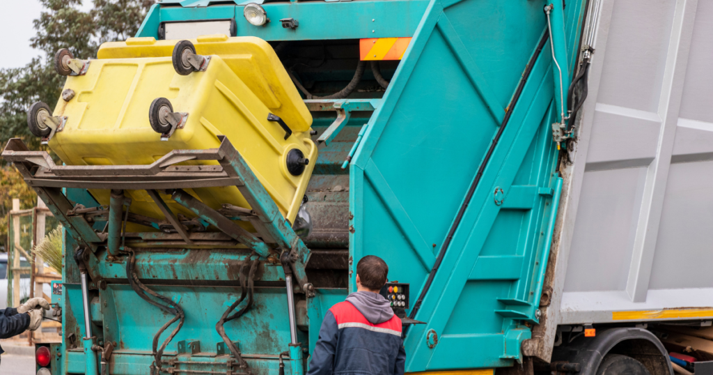 Garbage truck loading a yellow waste bin as part of waste removal services.